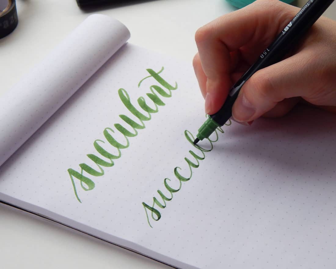 Ręka prawidłowo trzymająca pisak kaligraficzny z widocznym kątem 45 stopni do kartki